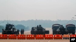 FILE - Myanmar's military stand guard at a checkpoint manned with an armored vehicles blocking a road leading to the parliament building, Feb. 2, 2021, in Naypyitaw. 