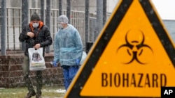 Seorang petugas medis dan seorang pria berbincang dekat rumah sakit isolasi Botkin, yang menjadi tempat perawatan diduga pasien virus corona, di St.Petersburg, Rusia, 16 Maret 2020. 