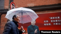 A man walks with an umbrella past a picture of Chinese President Xi Jinping on a street ahead of the National People's Congress (NPC), in Shanghai, March 2, 2021.
