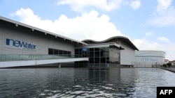 This picture taken on July 27, 2021 shows a tank (R) for processed used water storage outside the Bedok NEWater plant in Singapore. - Giant pumps whir deep underground at the plant in Singapore that helps transform sewage into water so clean it is…