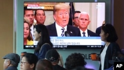 People pass by a TV screen showing a footage of U.S. President Donald Trump during a news program at the Seoul Railway Station in Seoul, South Korea, May 25, 2018. 