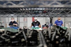 FILE - Ford Motor Company line workers put together ventilators that the automaker is assembling at the Ford Rawsonville plant in Ypsilanti Township, Michigan, May 13, 2020.