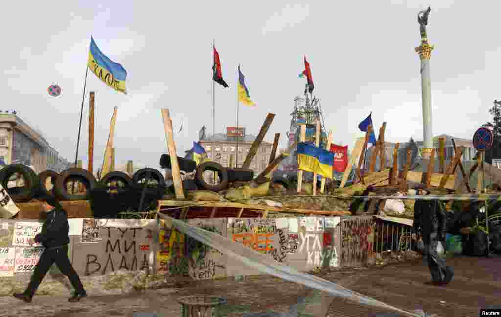 People pass by a barricade erected by pro-European integration protesters in central Kyiv, Dec. 13, 2013.
