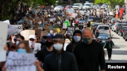 Protesters carry signs at a rally following the death in Minneapolis police custody of George Floyd, in Boston, Massachusetts, May 31, 2020. 