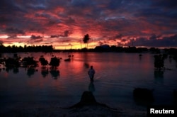 FILE - A villager wades through a small lagoon, which at high-tide laps at the base of homes, near the village of Tangintebu on South Tarawa in the central Pacific island nation of Kiribati, which consists of a chain of 33 atolls and islands that stand just met A villager wades through a small lagoon, which at high-tide laps at the base of homes, near the village of Tangintebu on South Tarawa in the central Pacific island nation of Kiribati.