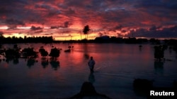 A villager wades through a small lagoon, which at high-tide laps at the base of homes, near the village of Tangintebu on South Tarawa in the central Pacific island nation of Kiribati, which consists of a chain of 33 atolls and islands that stand just met