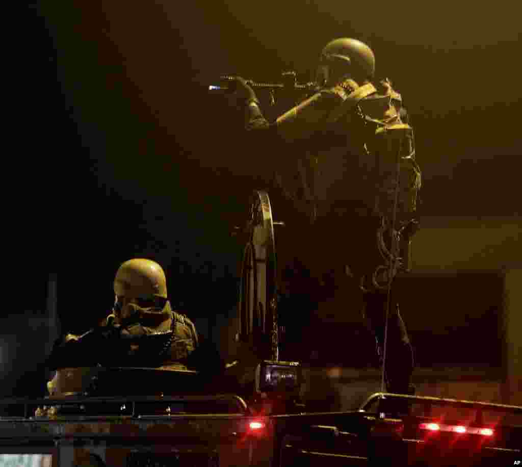 A law enforcement officer aims his rifle, Aug. 17, 2014, after tear gas was fired to disperse a crowd protesting the shooting of teenager Michael Brown last Saturday in Ferguson.