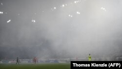 Kiper Freiburg dari Belanda, Mark Flekken berdiri di lapangan yang diselimuti asap di stadion dalam laga divisi satu Jerman Bundesliga antara SC Freiburg dan VfL Wolfsburg di Freiburg, 19 Mei 2023. (Foto: Thomas Kienzle/AFP)