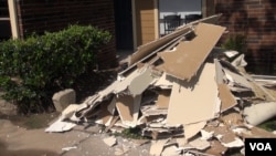 In some parts of Houston, there are piles of broken drywall outside apartment doors, as well as carpets and warped wood from floors and doorways. (G. Flakus/VOA)