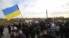 FILE - Ukrainian army veterans and volunteers wave the national flag at a checkpoint near the town of Zolote, Luhansk region, Ukraine, Oct. 9, 2019.