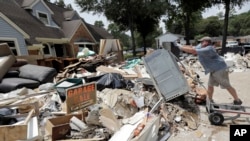 Volunteer Paul Hancock pushes an oven damaged by floodwaters onto a pile of debris in the aftermath of Hurricane Harvey on Sunday, Sept. 3, 2017, in Spring, Texas. 