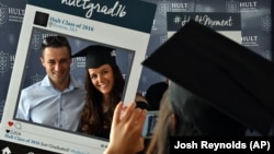 Hult International Business School graduate Victoria Stanciu and her fiance pose as her classmate takes a photo after the graduation ceremony in Boston