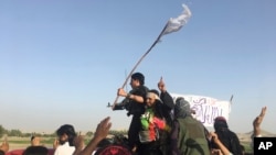 FILE - Taliban fighters greet residents in the Surkhroad district of Nangarhar province, east of Kabul, Afghanistan, June 16, 2018. 