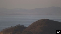 A North Korean ship passes between the North Korean mainland, background, and the South Korean island of Yeonpyeong, foreground, 26 Nov 2010