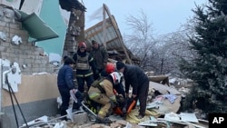 Los rescatistas ayudan a una persona herida después de que casas residenciales fueran destruidas por un ataque con misiles rusos, en Novomoskovsk, cerca de Kryvyi Rih, Ucrania, el 8 de enero de 2024. (Servicio de Emergencia de Ucrania vía AP)