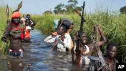 Rebel soldiers protect ethnic Nuer civilians as they walk through flooded areas to reach a UN camp for the displaced in Bentiu, Unity state in Sept. 2014.