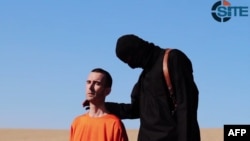 An image grab taken from a video released by the Islamic State (IS) and identified by private terrorism monitor SITE Intelligence Group purportedly shows British aid worker David Haines dressed in orange and on his knees in a desert landscape speaking to 