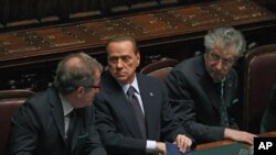 Italian Prime Minister Silvio Berlusconi (C) holds and saves a memo reading "308 [the result of the vote] - 8 traitors - political reversal - vote - take note: resign - Republic President - a solution" during a budget vote at the parliament in Rome, Novem