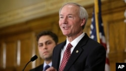 Arkansas Gov. Asa Hutchinson answers reporters' questions as Sen. Jonathan Dismang, R-Beebe, background, listens at the state Capitol in Little Rock, Ark., Wednesday, April 1, 2015.