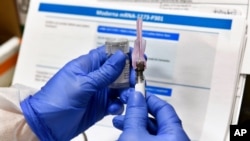FILE - A nurse prepares a shot that is part of COVID-19 vaccine developed by the National Institutes of Health and Moderna Inc., in Binghamton, New York, July 27, 2020. 
