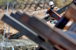 A government contractor, surrounded by existing Normandy barriers that separate Mexico and the United States, pours a concrete footer in preparation for a section of Pentagon-funded border wall along the Colorado River, Sept. 10, 2019, in Yuma, Ariz.