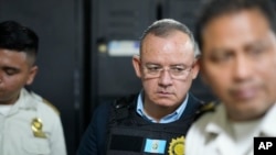 El exministro de Gobernación, Napoleón Barrientos, es escoltado por la policía mientras espera su audiencia en la corte de la Ciudad de Guatemala, el jueves 11 de enero de 2024. Barrientos fue arrestado el jueves por supuestamente no cumplir con sus deberes.
