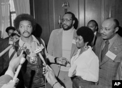 Jesse Jackson speaks to reporters at the Operation PUSH Soul Picnic in New York, March 26, 1972, as Tom Todd, vice president of PUSH, from second left, Aretha Franklin and Louis Stokes look on.