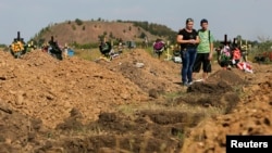 FILE - People stand near graves at a municipal graveyard on the edge of Donetsk, eastern Ukraine, August 21, 2014. Up to 2,000 civilian lives have been lost in the more than two-year-old conflict there, according to U.N. figures.