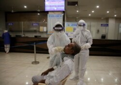 A health worker takes a nasal swab sample to test for COVID-19 at a state bus station in Ahmedabad, India, Aug. 29, 2020.