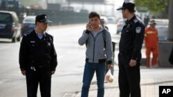 Chinese policemen watch as a man walks near the Beijing No. 3 Intermediate Court in Beijing, April 17, 2015, during the trial of a journalist.