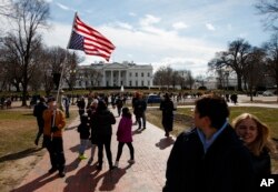 A man walks with an American flag flying upside down during a protest Feb. 18, 2019, in Lafayette Square in front of the White House in Washington, to protest that President Donald Trump declared a national emergency along the southern border.