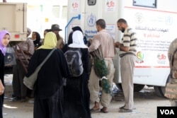 Faris Yahyia, center, carries peacocks onto the truck, his neighbor's valuable and well-loved pets, after fleeing his home through gunfire, in Mosul, Iraq, June 4, 2017. (H. Murdock/VOA)