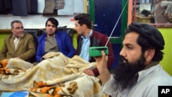 FILE - An Afghan shopkeeper, right, listens to Islamic State radio at his shop in Jalalabad, capital of Nangarhar province, Afghanistan, Jan. 10, 2016.