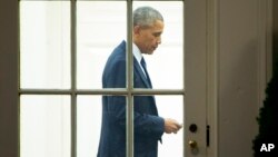 FILE - President Barack Obama checks his mobile phone inside the Oval Office of the White House in Washington, Jan. 28, 2016. Obama has viewed technology as key to making the sprawling federal government more efficient and responsive to the public.