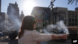 Stephanie Drake burns sage on Canal and Bourbon Street, Jan. 2, 2025, in New Orleans.