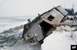 FILE - In this Dec. 8, 2006, file photo, Nathan Weyiouanna's abandoned house at the west end of Shishmaref, Alaska, sits on the beach after sliding off during a fall storm in 2005.