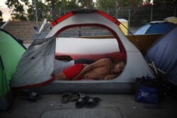 A Cuban migrant sleeps inside a tent at the foot of the Puerta Mexico bridge in Matamoros, Mexico, that crosses the border to Brownsville, Texas, Aug. 4, 2019.