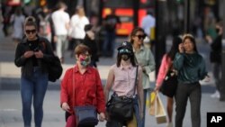 FILE - Shoppers, some wearing masks, walk on Oxford Street in London, Britain, Sept. 21, 2020.