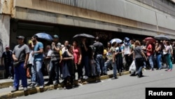 FILE - People queue up to try to buy basic food items outside a supermarket in Caracas, Venezuela, April 28, 2016. 