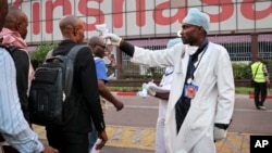 FILE - A health worker checks people's temperatures as they disembark a plane at the airport in Kinshasa, Congo, June 2, 2018.