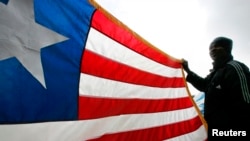 FILE - A Liberian refugee holds a Liberian flag.