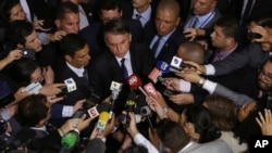 FILE - Reporters ring Brazil's President Jair Bolsonaro in Brasilia, May 7, 2019. Bolsonaro repeated a debunked sexually charged allegation about one of the nation’s prominent journalists on Feb. 18, 2020, drawing fire from press freedom advocates.
