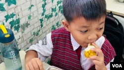 A boy tries his first free meal at Susukan public elementary school in Jakarta, Indonesia. (Devianti Faridz/VOA)