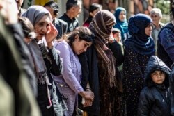 FILE - Iraqi Yazidi women and children rescued from the Islamic State group wait to board buses bound for Sinjar in Iraq's Yazidi heartland, April 13, 2019.