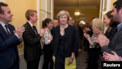 Staff applaud as Britain's new Prime Minister Theresa May, and her husband Philip, walk into 10 Downing Street after May had met Queen Elizabeth in Buckingham Palace, in central London, Britain, July 13, 2016. 