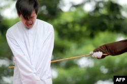 FILE - One of two Indonesian men is publicly caned for having sex, in a first for the Muslim-majority country where there are concerns over mounting hostility towards the small gay community, in Banda Aceh, May 23, 2017.