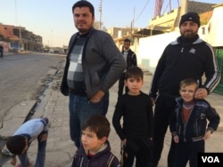 Arabic language teacher Nathir Bashir and his family stand outside their Mosul home as mortars and gunfire can be heard in the next neighborhood in Mosul, Iraq, Nov. 27, 2016. (H. Murdock/VOA)