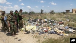 In this image made from video, Iraqi Shi'ite militiamen stand near a mass grave, believed to contain the bodies of Iraqi soldiers killed by Islamic State group militants when they overran Camp Speicher military base last June, in Tikrit, Iraq, April 2, 20