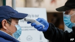 A security guard takes the temperature of a customer at a shopping precinct in Sydney, Australia, Jan. 3, 2021.
