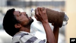 Seorang pria minum air dari botol di tengah hari yang terik di Allahabad, India (31/5). (AP/Rajesh Kumar Singh)